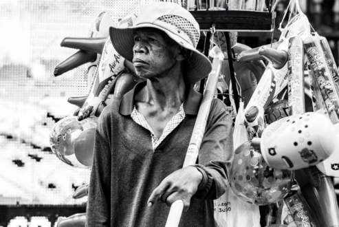 Vendor Amidst Inflatable Toys - Fine Art Photography Print, Limited Edition Photography, Documentary Photography, Black and White Photography, Art Photography for Sale