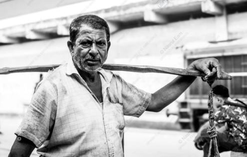 Man with a Carrying Beam - photography portrait, visual storytelling, black and white photography, light and composition, human dignity, documentary photography