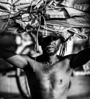 The Porter Under a Sunlit Burden - Visual Storytelling in Photography Books, Documentary Photography Techniques, Monochrome Fine Art Photography, Photography Composition Masterclass, Human Spirit Photography, Photographic Endurance Study