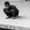A Boy Crouching on a Concrete Ledge