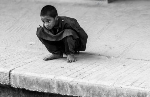 A Boy Crouching on a Concrete Ledge