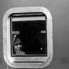 A Traveler's Face in a Riveted Window